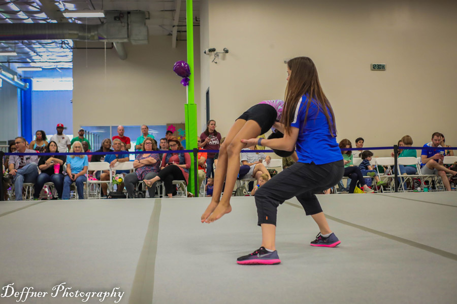 Coach helps gymnast with her back handspring at competition.
