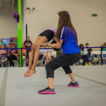 Coach helps gymnast with her back-handspring at Skills Meet.